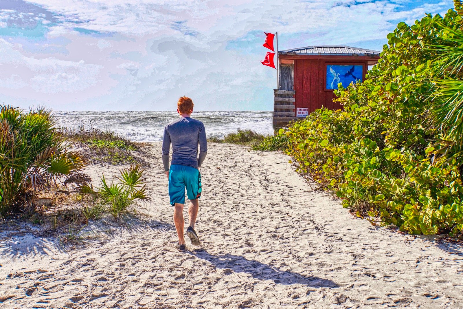 Young Sarasota boy strolls toward lifeguard stand on Lido Beach, Sarasota, Florida, following Hurricane Milton