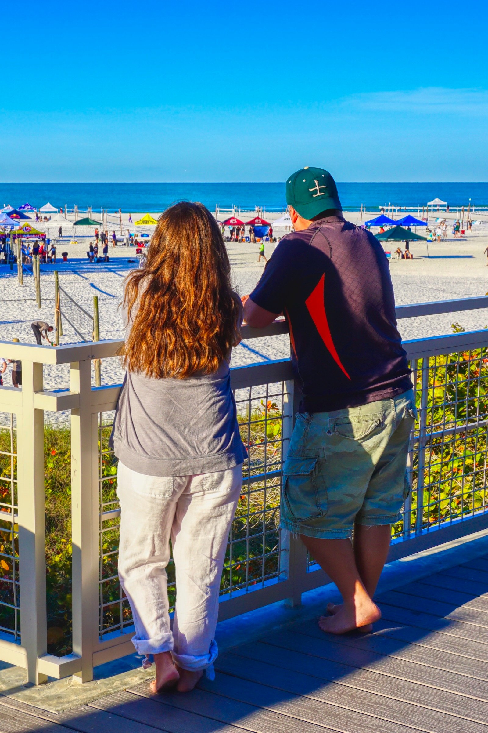 Atop the sun deck at Siesta Key Beach, a couple looks out onto the collegiate women's beach volleyball tourney