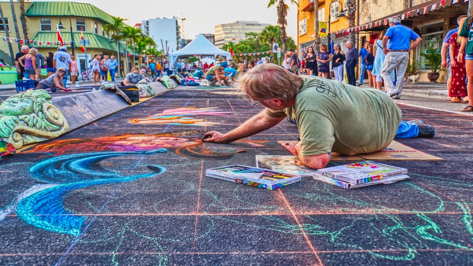 Artist leans into his chalk art project at the Sarasota Chalk Festival in Burns Court