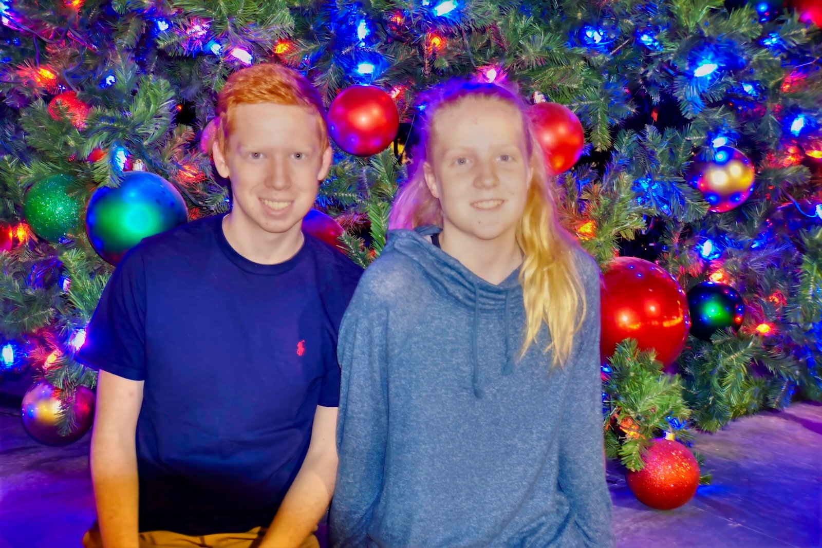 kids slow down to pose for a photo in front of the Christmas tree at UTC Christmas